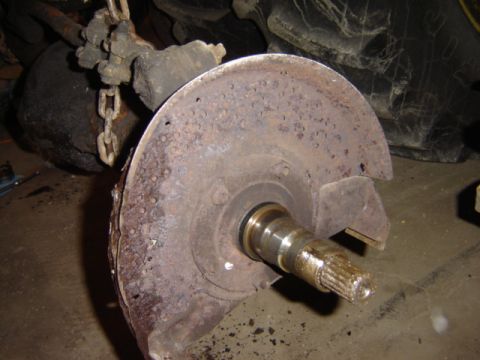 1992 Ford Bronco - A heavily rusted brake rotor and hub assembly is shown, with a splined shaft extending from the center.