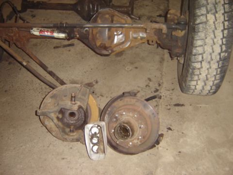 1992 Ford Bronco - Disassembled Ford Bronco rear axle and front brake parts laid out on a concrete floor.