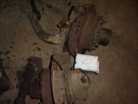 1992 Ford Bronco - Close-up view of old, rusty vehicle suspension parts laid out on a concrete floor.