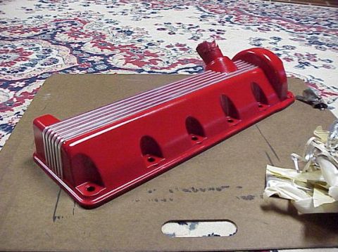 2002 Ford Mustang - A red finned valve cover with silver accents sits on a cardboard surface.