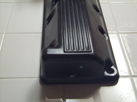 2002 Ford Mustang - A close-up view of a black engine valve cover, likely a replacement part, shown on a tiled background.
