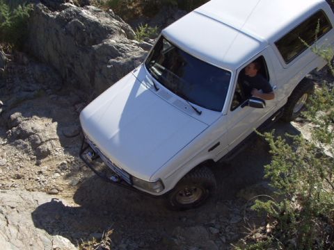1993 Ford Bronco - A white 1993 Ford Bronco is shown off-roading on a rocky trail.