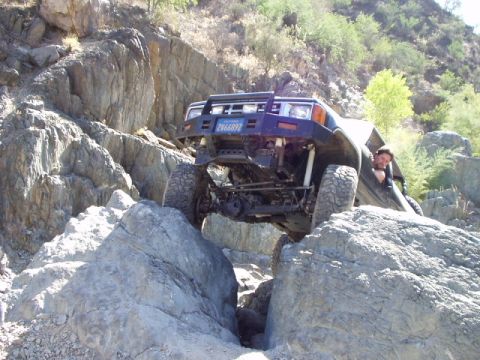 1993 Ford Bronco - This modified SUV is tackling a challenging rocky trail, demonstrating its off-road capabilities.