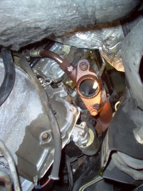 1994 Ford Crown Victoria - Close-up view of an exhaust manifold flange, showing signs of rust and surrounding heat shielding.