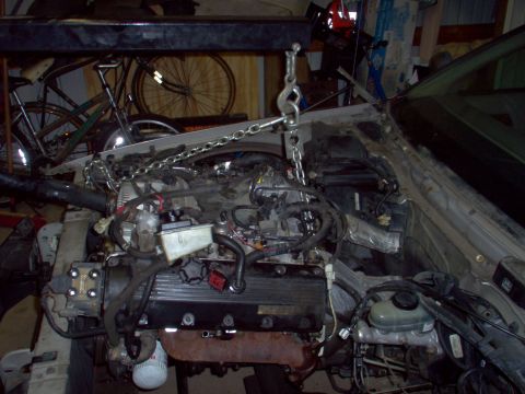 1994 Ford Crown Victoria - The engine is suspended by chains and a hoist, ready for removal from the vehicle.