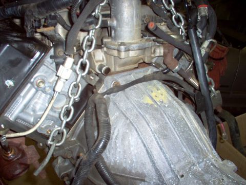1994 Ford Crown Victoria - Engine and transmission assembly, likely being removed or installed, with chains secured for lifting.