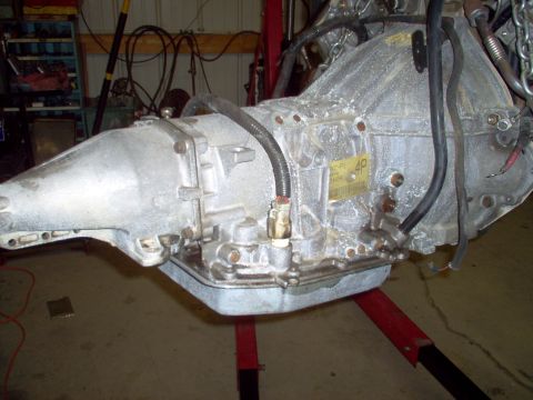 1994 Ford Crown Victoria - A transmission part, possibly from an engine donor, is mounted on an engine stand. A label on the part reads '4D'.