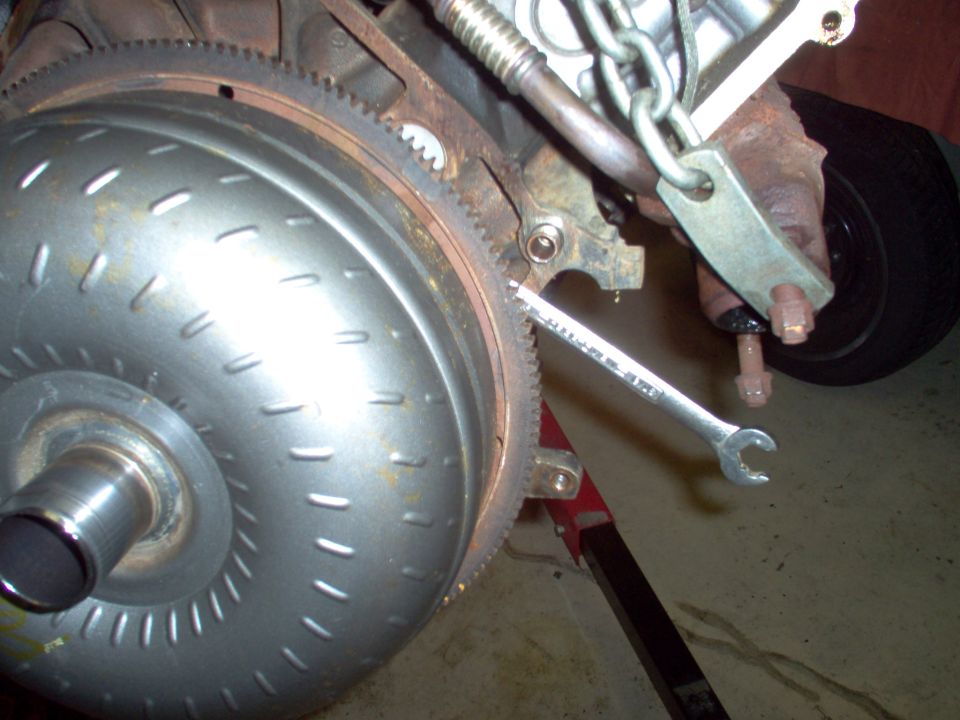 Torque converter on engine flexplate with starter, chain and wrench in garage