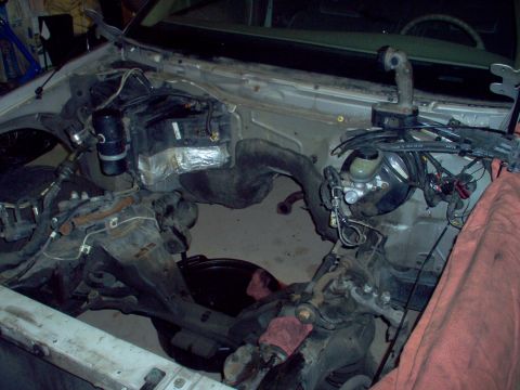 1994 Ford Crown Victoria - The engine bay of a car is shown with the engine removed, revealing the chassis and various mechanical parts.