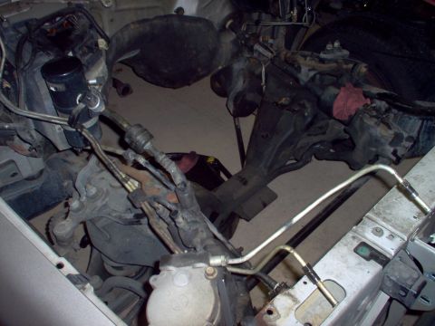 1994 Ford Crown Victoria - Close-up view of engine bay components, including hoses and metal lines, with a portion of a silver fender.