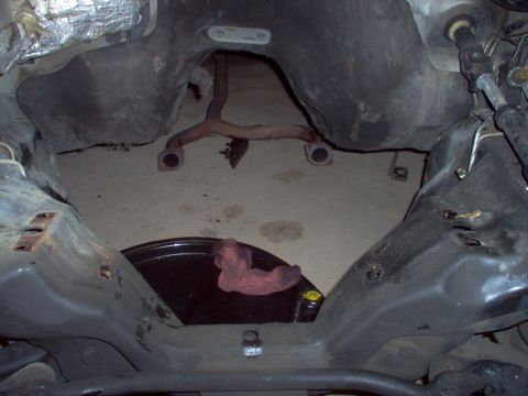 1994 Ford Crown Victoria - The undercarriage of a vehicle is shown, with exhaust pipes and a drain pan visible.