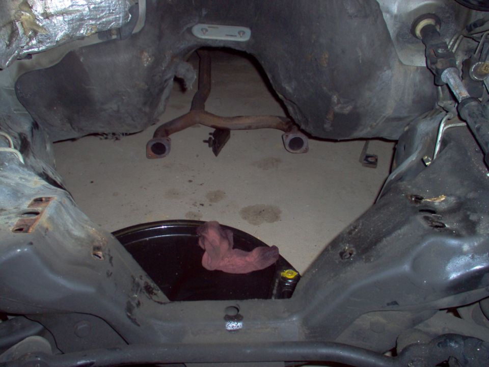 Underside of car showing empty transmission area, exhaust Y-pipe and pink rag