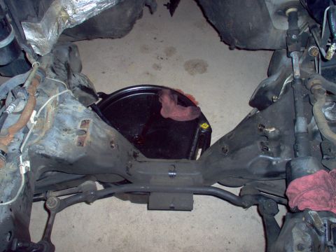 1994 Ford Crown Victoria - Underside view of a vehicle's frame and engine bay, showing mechanical parts and a drain pan.