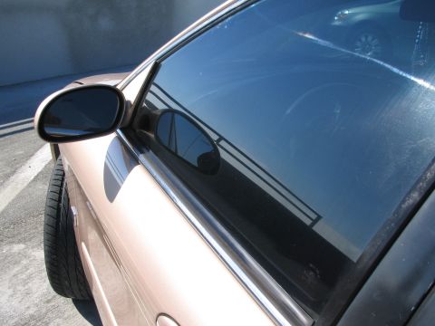 1997 Mercury Sable - Side view of a tan car with a reflection of a railing and another vehicle in the window.