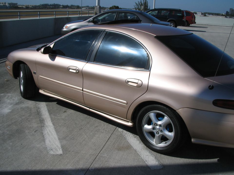 1997 Mercury Sable sedan, tan color, parked in a lot with other vehicles