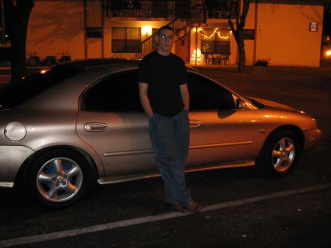 1997 Mercury Sable - A man poses next to a gold sedan at night in front of an apartment building.