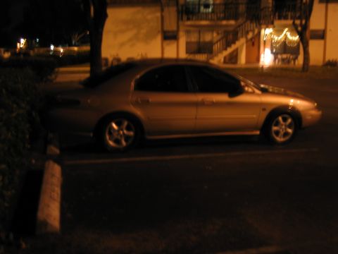 1997 Mercury Sable - A silver sedan is parked in a lot at night, showing its side profile and alloy wheels.