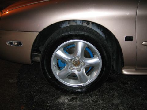 1997 Mercury Sable - Close-up of a 1997 Mercury Sable's front wheel, a silver alloy rim and bright blue brake calipers.
