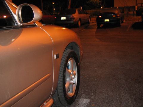 1997 Mercury Sable - A car's fender and wheel are visible in the foreground with other vehicles parked behind.