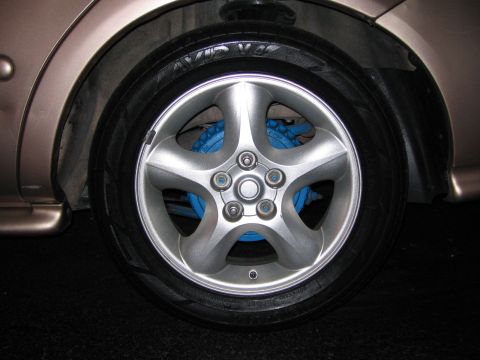 1997 Mercury Sable - A close-up view of a vehicle's wheel and tire, with bright blue brake calipers visible through the spokes.