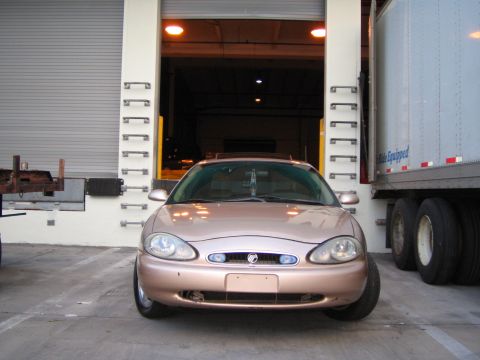 1997 Mercury Sable - Rose gold 1997 Mercury Sable parked in front of a loading dock, with a semi-trailer to the right.