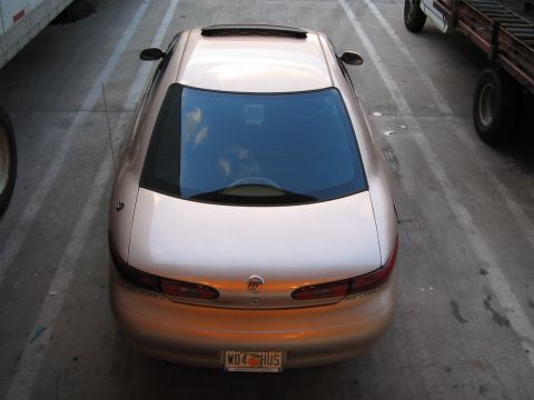 1997 Mercury Sable - A gold 1997 Mercury Sable is viewed from above, parked between a trailer and a truck.