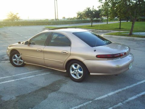 1997 Mercury Sable - A gold 1997 Mercury Sable sedan is viewed from the rear quarter angle in a parking lot.
