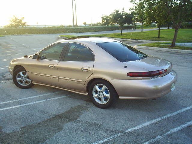 Gold 1997 Mercury Sable sedan parked in a lot, rear quarter view