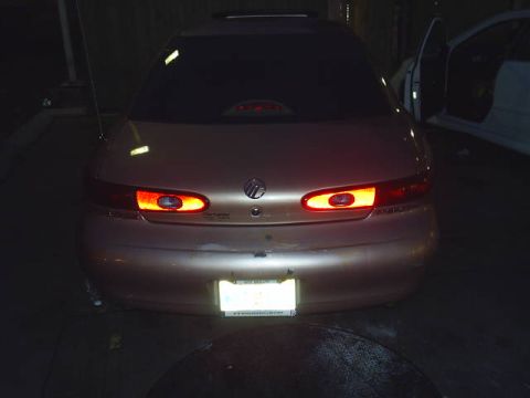 1997 Mercury Sable - Rear view of a 1997 Mercury Sable with brake lights illuminated. A second vehicle is parked nearby.