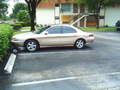 1997 Mercury Sable - Gold 1997 Mercury Sable parked in a lot next to bushes.