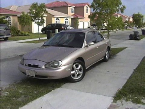 1997 Mercury Sable - A tan 1997 Mercury Sable sedan is parked on the side of a residential street.