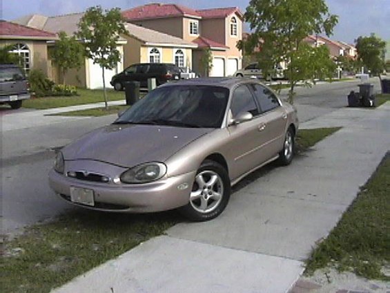 Tan 1997 Mercury Sable sedan parked on a suburban street, front 3/4 view
