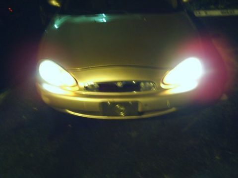 1997 Mercury Sable - Front view of a gold 1997 Mercury Sable, its headlights illuminated.