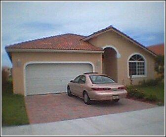 1997 Mercury Sable - A tan sedan is parked in the driveway of a single-family home with a tiled roof.