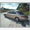 1997 Mercury Sable - A gold 1997 Mercury Sable sedan is viewed from the rear three-quarter angle on a sunny day.