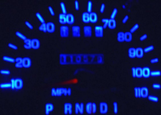 Speedometer with blue backlighting at night showing about 110,579 miles on the odometer