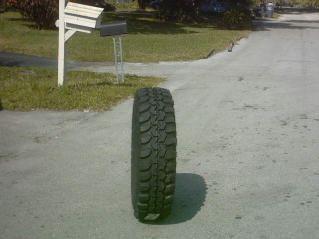 Off-road tire on asphalt, side view. Tread is deep with large blocks