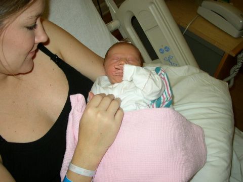 1995 Ford Bronco - A mother cradles her newborn baby, swaddled in a pink blanket, in a hospital room.