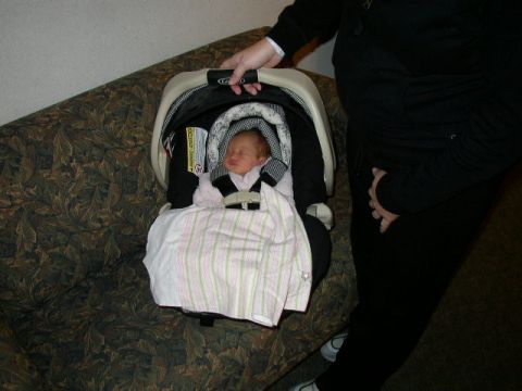 1995 Ford Bronco - A baby sleeps soundly in a car seat placed on a couch, with a person standing nearby.