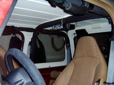 1998 Jeep TJ - The interior of a Jeep features a CB radio mounted above the passenger seat and a view through the rear window.