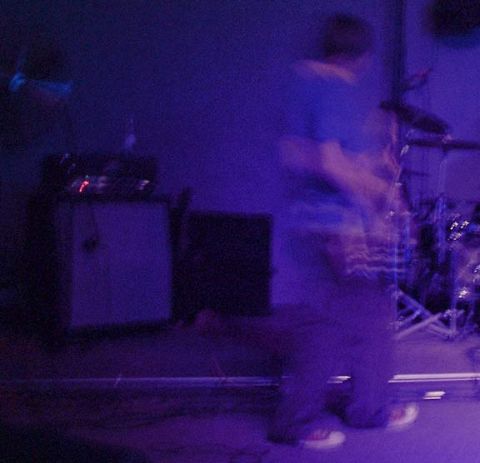 1993 Ford Probe - A blurry figure plays guitar on a stage under blue lights, with a drum set visible.
