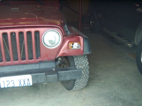 1998 Jeep TJ - Front corner of a red 1998 Jeep TJ, showing the grille, headlight, and license plate.