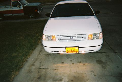2000 Ford Crown Victoria - White 2000 Ford Crown Victoria parked in front of a driveway, with another truck visible in the background.