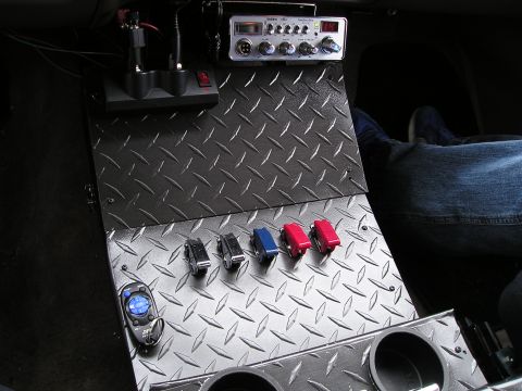 1996 Ford Bronco - A custom center console features a CB radio, switches, and a remote control, with a person's legs visible in the background.