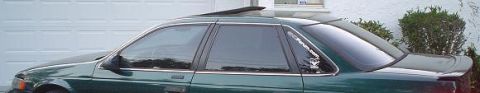 1993 Ford Taurus - The side profile of a 1993 Ford Taurus sedan, a sunroof and a rear spoiler.