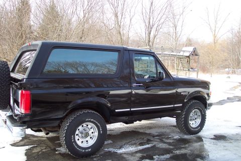 1995 Ford Bronco - A black 1995 Ford Bronco SUV is parked outdoors in a snowy environment, viewed from the side.