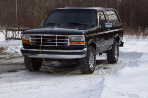 1995 Ford Bronco - Black 1995 Ford Bronco sits in a snowy outdoor lot with a yellow cord running near the front tire.