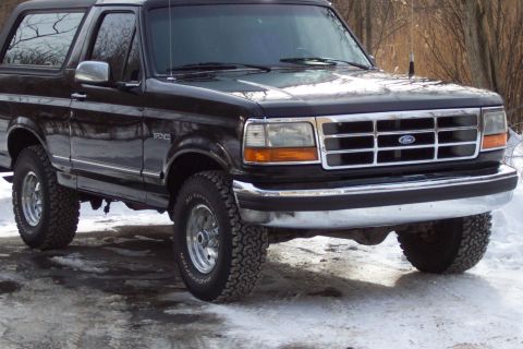 1995 Ford Bronco - This black Ford Bronco is shown from a three-quarter front angle in a snowy outdoor setting.
