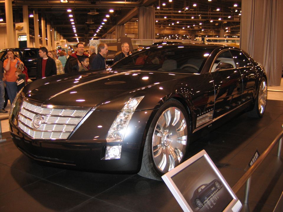 Long dark Cadillac Sixteen concept sedan with large chrome wheels on show floor