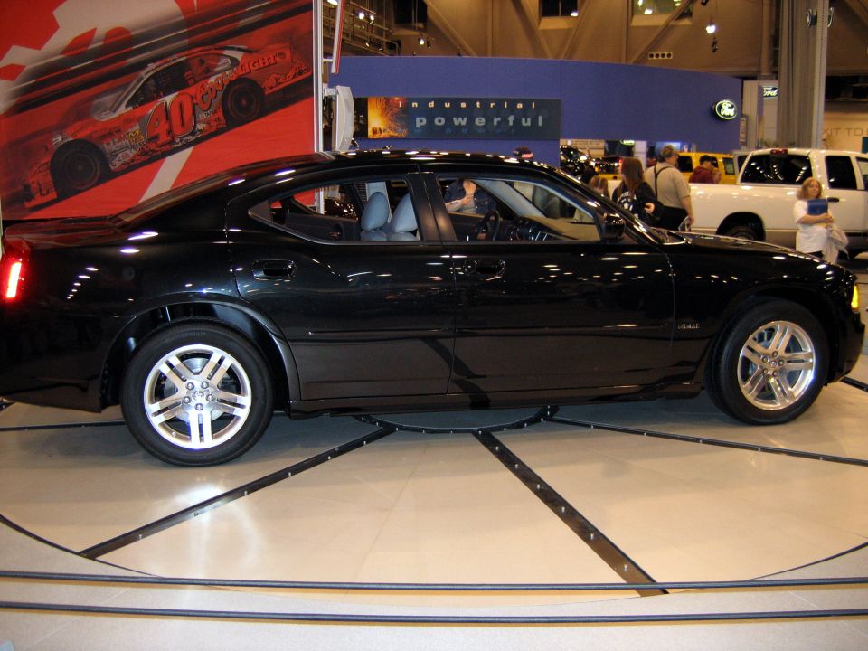 Black Dodge Charger sedan, side profile on a turntable at an auto show